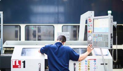 A man leaning over the CNC turning machine while intently observing the machining process