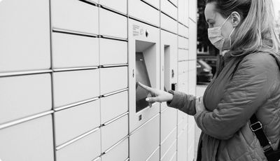 A woman using a touch-screen that's connected to the self-service parcel terminal.